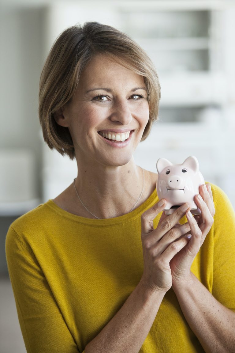 Portrait of smiling woman holding a piggy bank